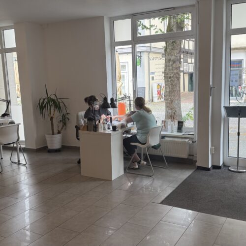Zwei  Personen  mit  neutralem  Blick  arbeiten  an  weißem  Tisch  im  hellen  Büro